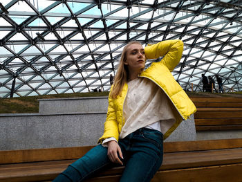 Young woman smiling while standing against yellow wall