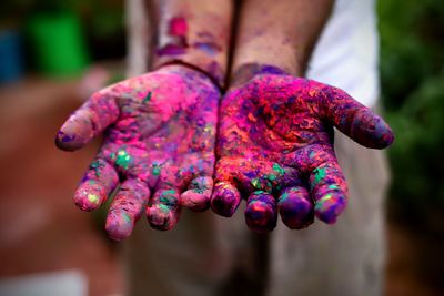 Cropped hands with multi colored powder paint