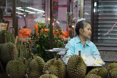 Woman selling durian fruit at market stall