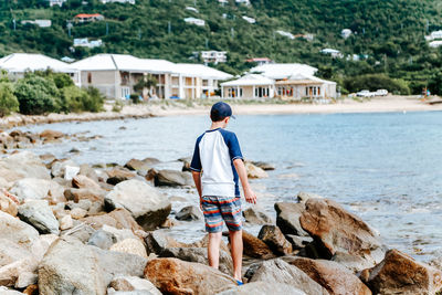 Rear view of man standing on rock at beach