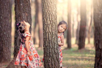 Portrait of cute girl with sister standing in forest