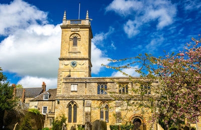 Low angle view of clock tower amidst buildings against sky