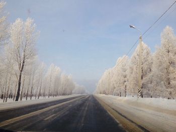 Road amidst bare trees against sky during winter