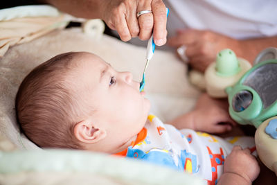 Baby being fed first solid meal with a blue spoon.