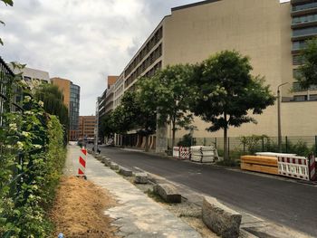 Road by buildings in city against sky