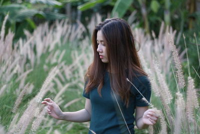 Young woman standing amidst plants on field