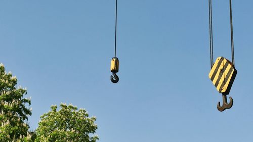 Low angle view of lighting equipment hanging against clear blue sky