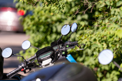 Many street-side scooter mirrors parked against a defocused urban background, closeup