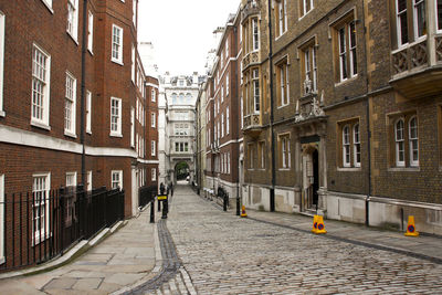 Rear view of man walking on footpath amidst buildings