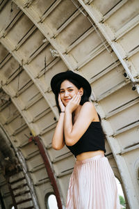 Portrait of smiling woman standing against built structure