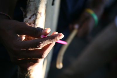 Close-up of hand holding pen by wall