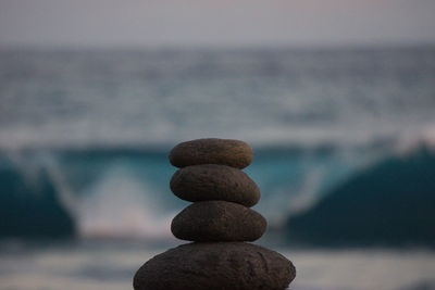 Stack of pebbles in sea against sky