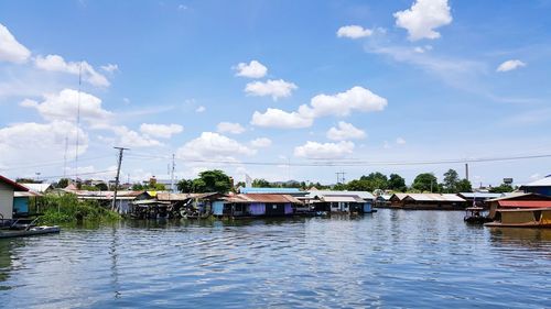 Houses by lake against blue sky during sunny day