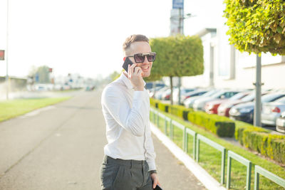 Young man talking on smart phone while standing in city