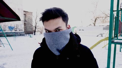 Portrait of young man standing on snow covered landscape during winter