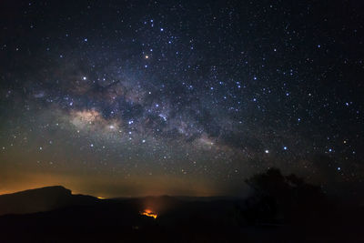 Silhouette mountain against star field at night