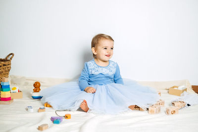 Cute baby girl in blue princess dress playing with toys at home. kids dresses for prom and birthday