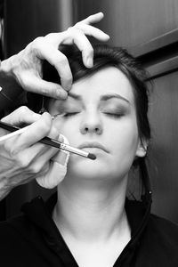 Cropped hands of beautician applying make-up to woman