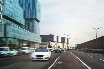 Cars on road in city against sky