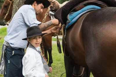 Argentinian father and daughter preparing horses to ride