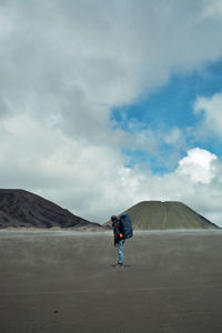 Side view of man on land against mountains and sky