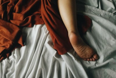 Low section of baby lying on bed