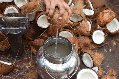 Cropped hand of man pouring coconut water in container