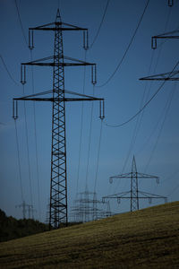 Low angle view of electricity pylon on field against sky