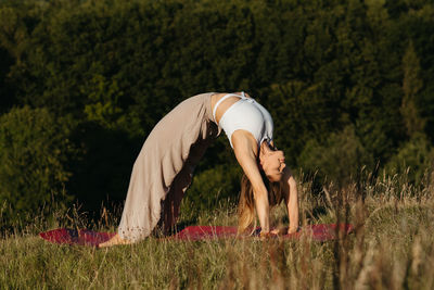 Young woman doing bridge exercise during yoga practice outdoors with beautiful background	
