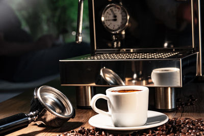 Close-up of coffee by portafilter and espresso maker on table