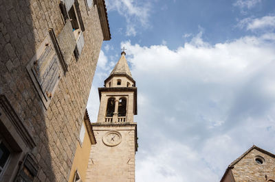 Low angle view of clock tower amidst buildings against sky