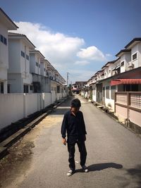 Boy walking on road against sky