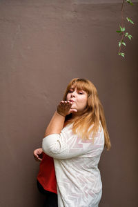 Beautiful young woman standing against wall