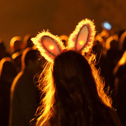 Rear view of woman with back lit bunny ears on bonfire night