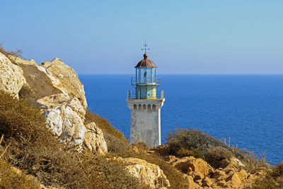 Lighthouse at beach against clear blue sky