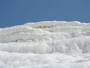 Snow covered landscape against clear blue sky