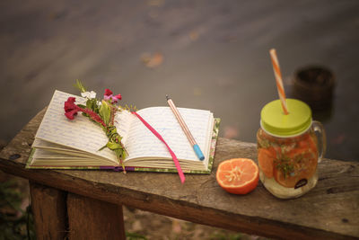 High angle view of drink by open diary on wooden table