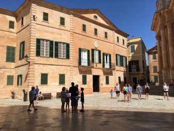 People walking on building against clear sky