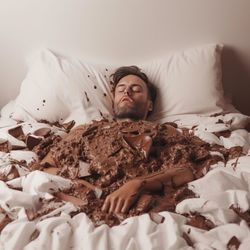 Man dipped in chocolate while on the bed.