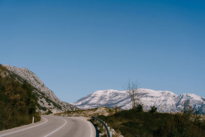 Road amidst mountains against clear blue sky