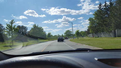 Cars on road against sky seen through car windshield