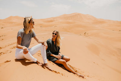 Woman sitting on sand dune in desert