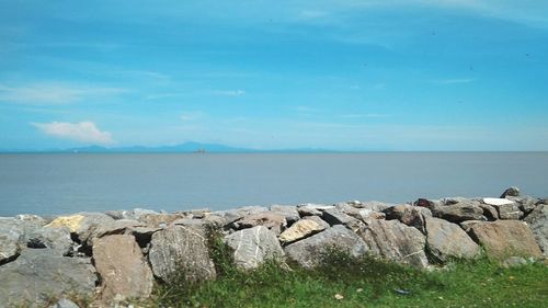 Rocks by sea against blue sky