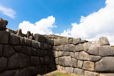 Low angle view of stone wall against cloudy sky