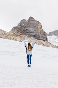 Young millennial girl enjoys the views of the alps standing on glacier