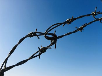 Low angle view of barbed wire against clear sky