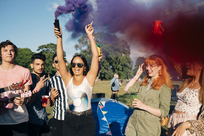 Woman holding distress flare while enjoying with friends during music concert