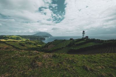 Scenic view of field and sea against sky