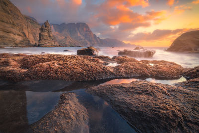Scenic view of sea by rock formation during sunset