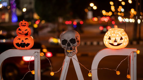 Close-up of skull and jack o lanterns with illuminated lighting at night